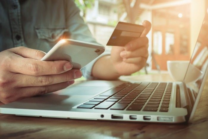 Person making payment online via mobile device and laptop